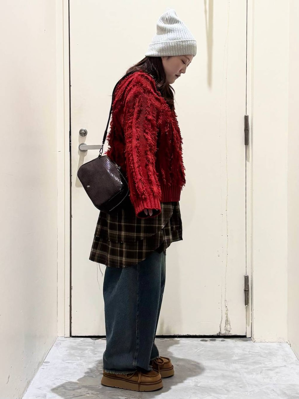 イエロー系のモカシン/デッキシューズ、ブルー系のデニムパンツ、レッド系のニット/セーターを着用したレディースの冬コーディネートの5枚目の写真