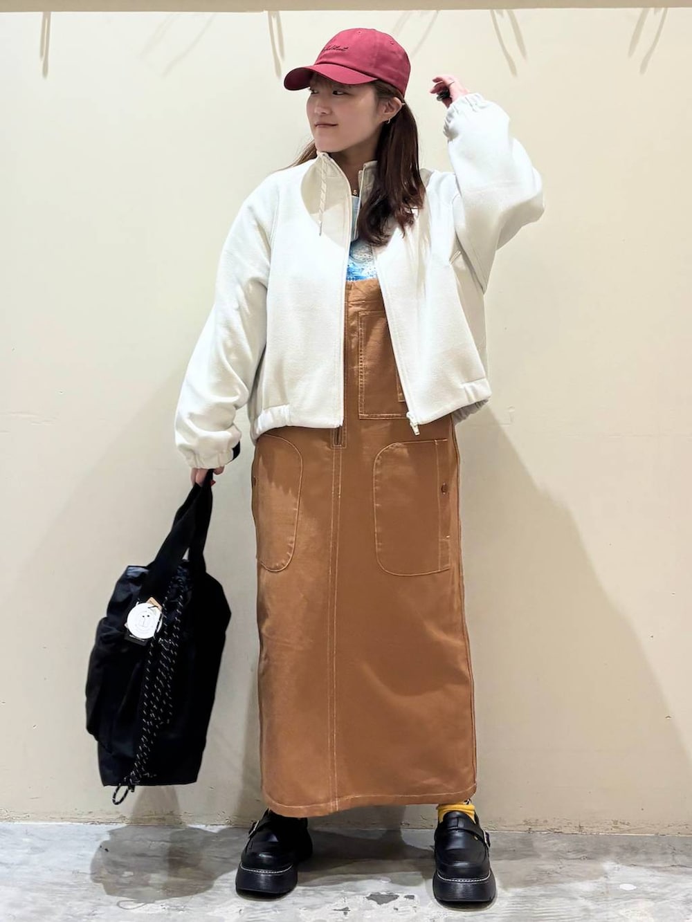 ブラック系のドレスシューズ、ブラウン系のジャンパースカート、ベージュ系のブルゾンを着用したレディースの冬コーディネートの2枚目の写真