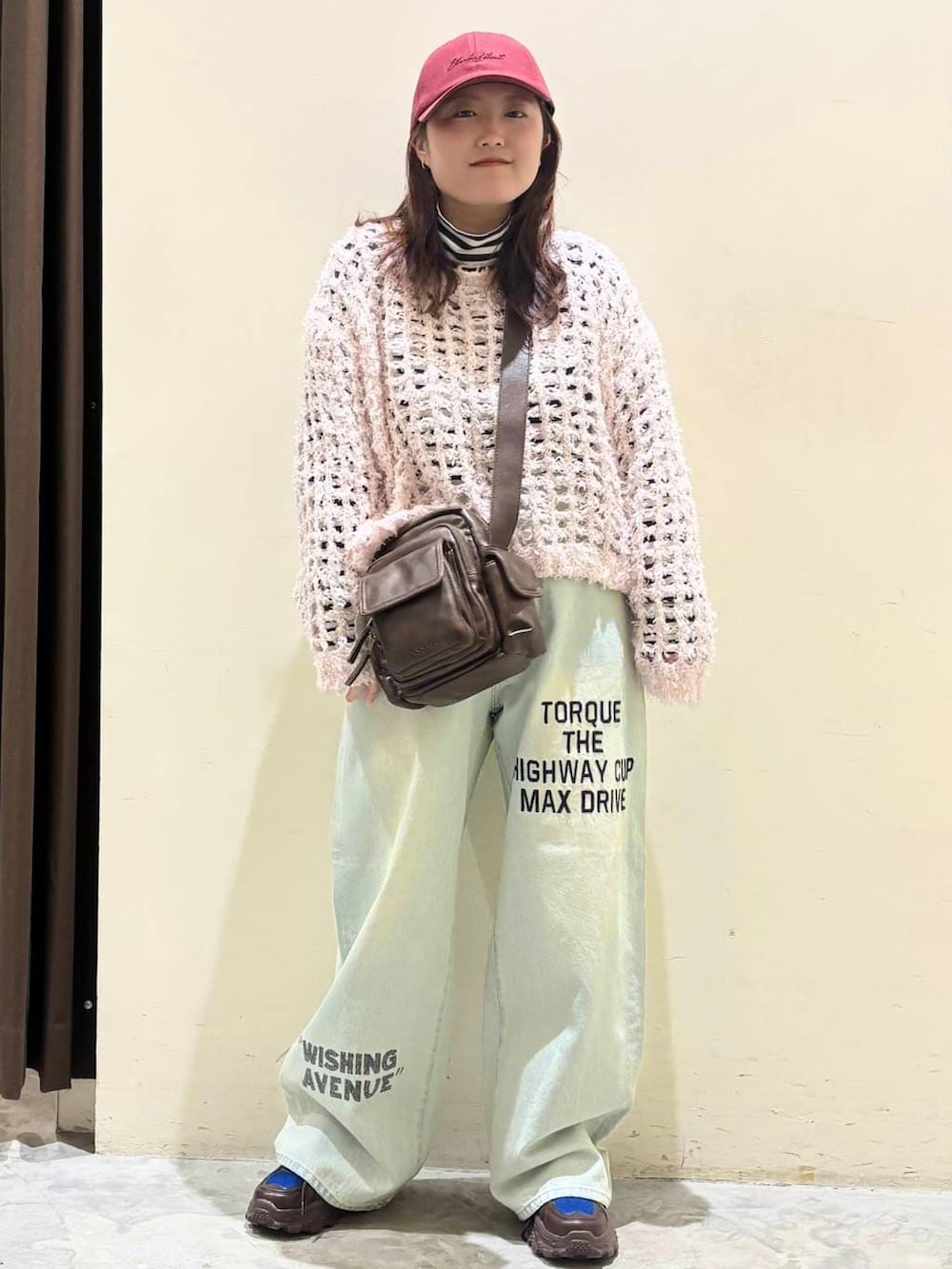 ブラウン系のスニーカー、ブラウン系のショルダーバッグ、ブルー系のデニムパンツを着用したレディースの冬コーディネートの3枚目の写真