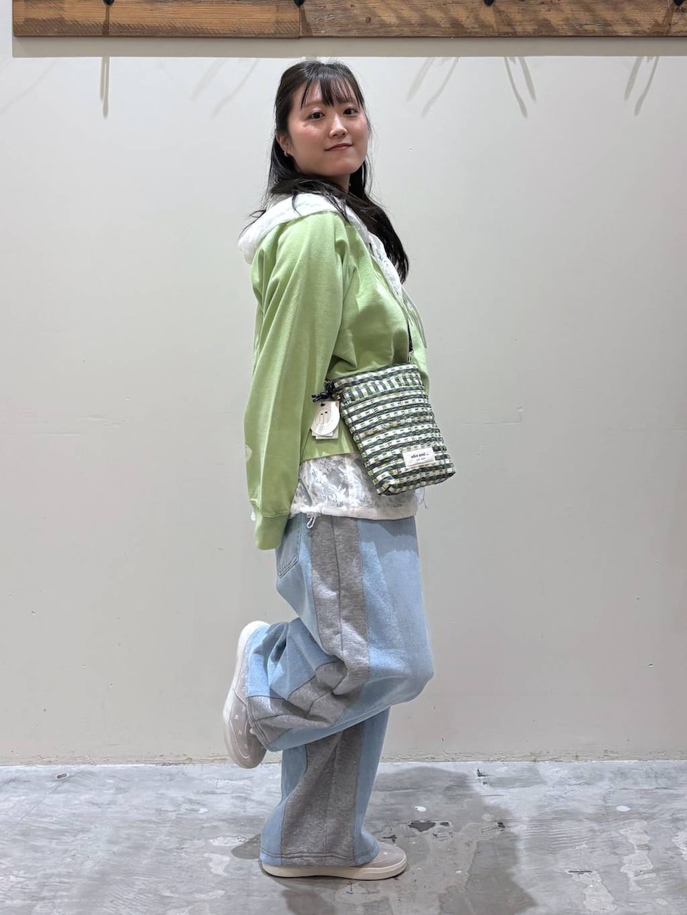 グレー系のデニムパンツ、グリーン系のショルダーバッグ、ホワイト系のベストを着用したレディースの春コーディネートの5枚目の写真