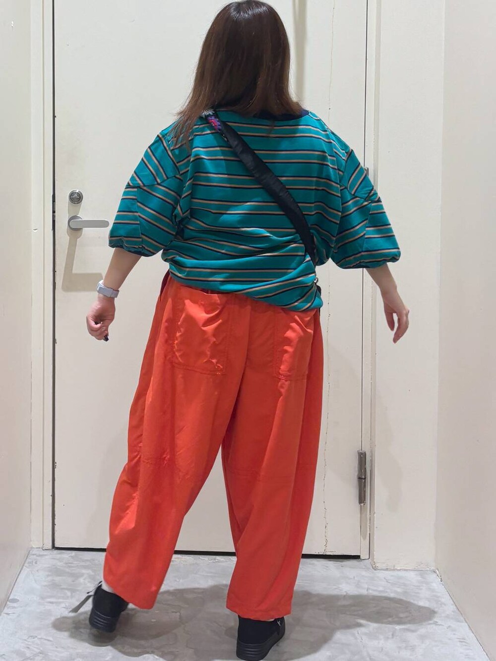 ブラック系のショルダーバッグ、オレンジ系のその他パンツ、グリーン系のTシャツ/カットソーを着用したレディースの夏コーディネートの7枚目の写真