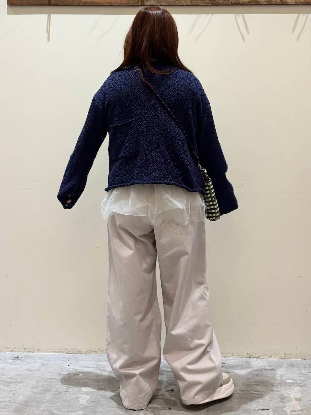 グリーン系のショルダーバッグ、ブルー系のニット/セーター、ベージュ系のチノパンツを着用したレディースの冬コーディネートの6枚目の写真