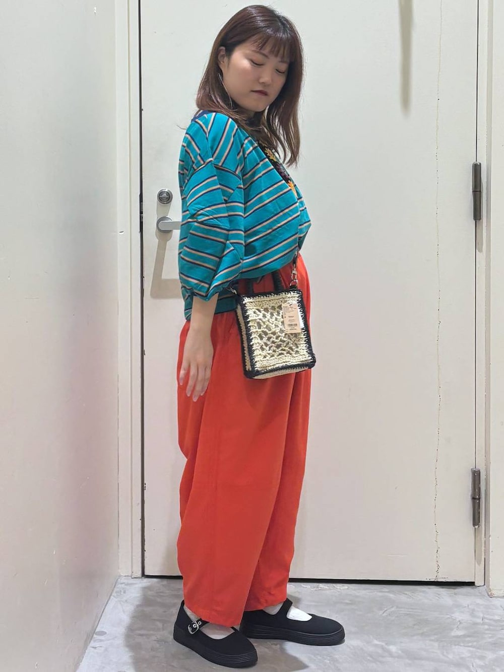 ブラック系のショルダーバッグ、オレンジ系のその他パンツ、グリーン系のTシャツ/カットソーを着用したレディースの夏コーディネートの6枚目の写真