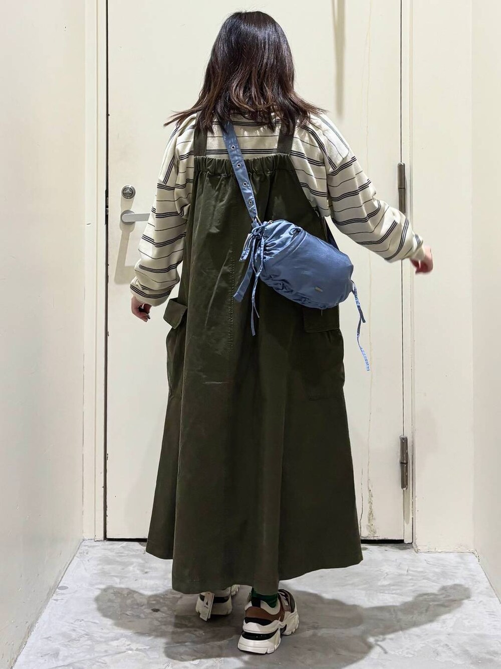 グリーン系のジャンパースカート、その他のスニーカー、ブルー系のショルダーバッグを着用したレディースの冬コーディネートの7枚目の写真