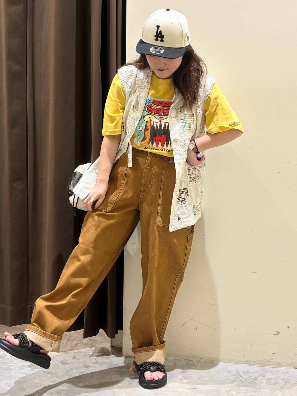 ベージュ系のベスト、ブラウン系のデニムパンツ、ブラック系のサンダルを着用したレディースの夏コーディネートの3枚目の写真
