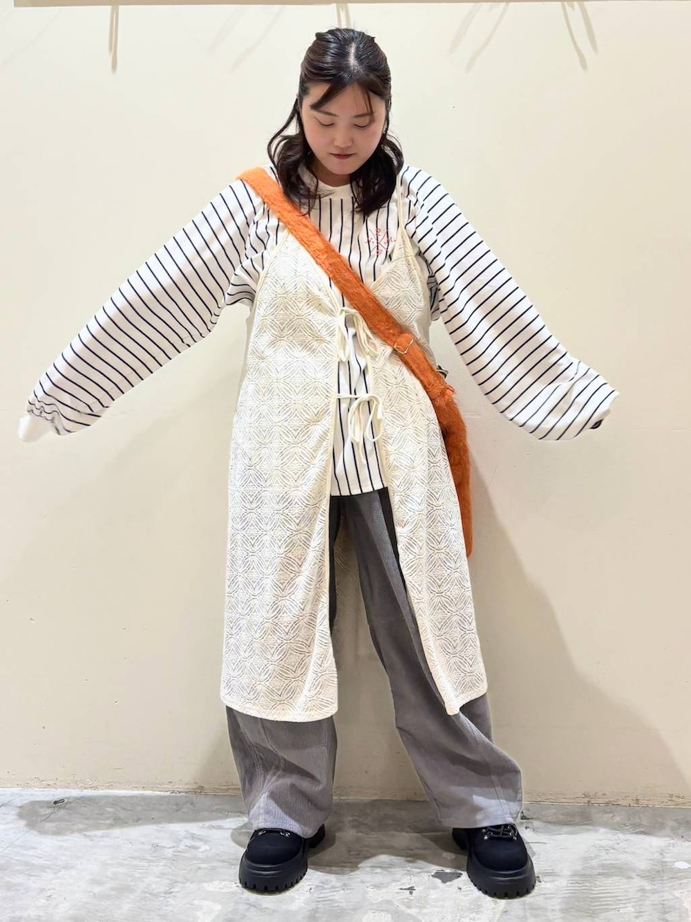 グレー系のその他パンツ、オレンジ系のトートバッグ、ブラック系のその他シューズを着用したレディースの秋コーディネートの2枚目の写真