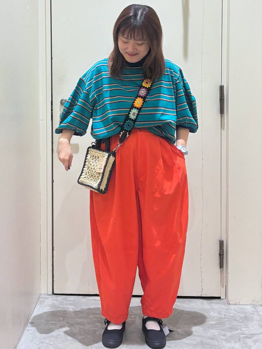 ブラック系のショルダーバッグ、オレンジ系のその他パンツ、グリーン系のTシャツ/カットソーを着用したレディースの夏コーディネートの2枚目の写真