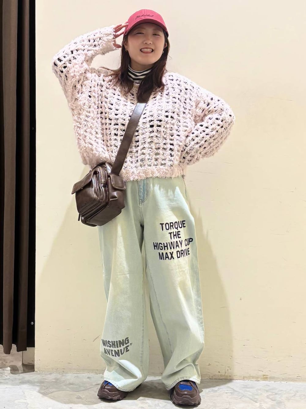 ブラウン系のスニーカー、ブラウン系のショルダーバッグ、ブルー系のデニムパンツを着用したレディースの冬コーディネートの4枚目の写真