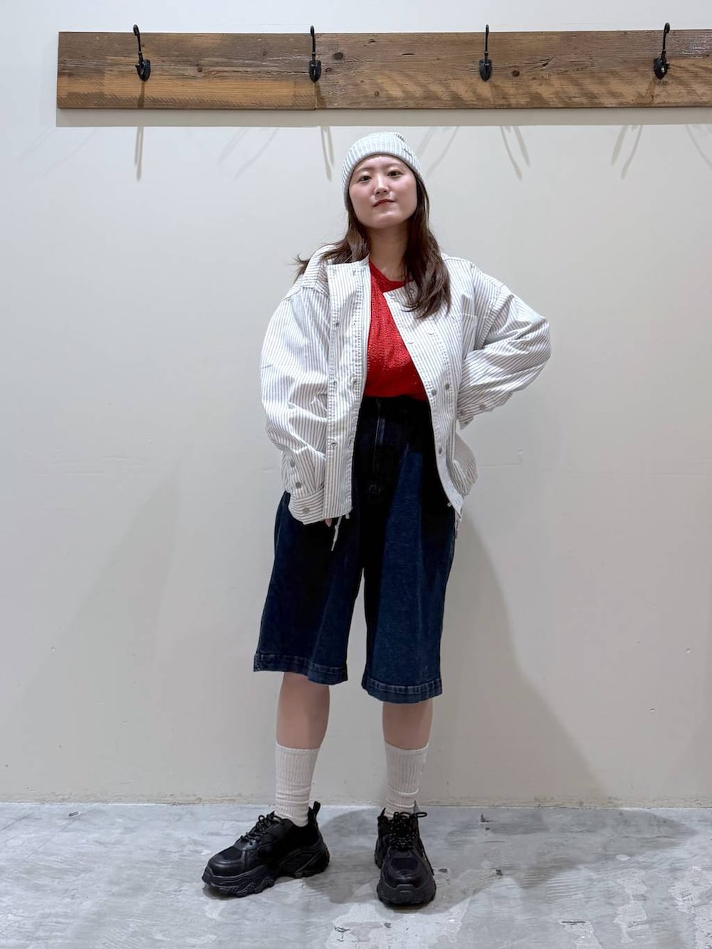 ブラック系のスニーカー、ベージュ系のカバーオール、レッド系のTシャツ/カットソーを着用したレディースの春コーディネートの2枚目の写真