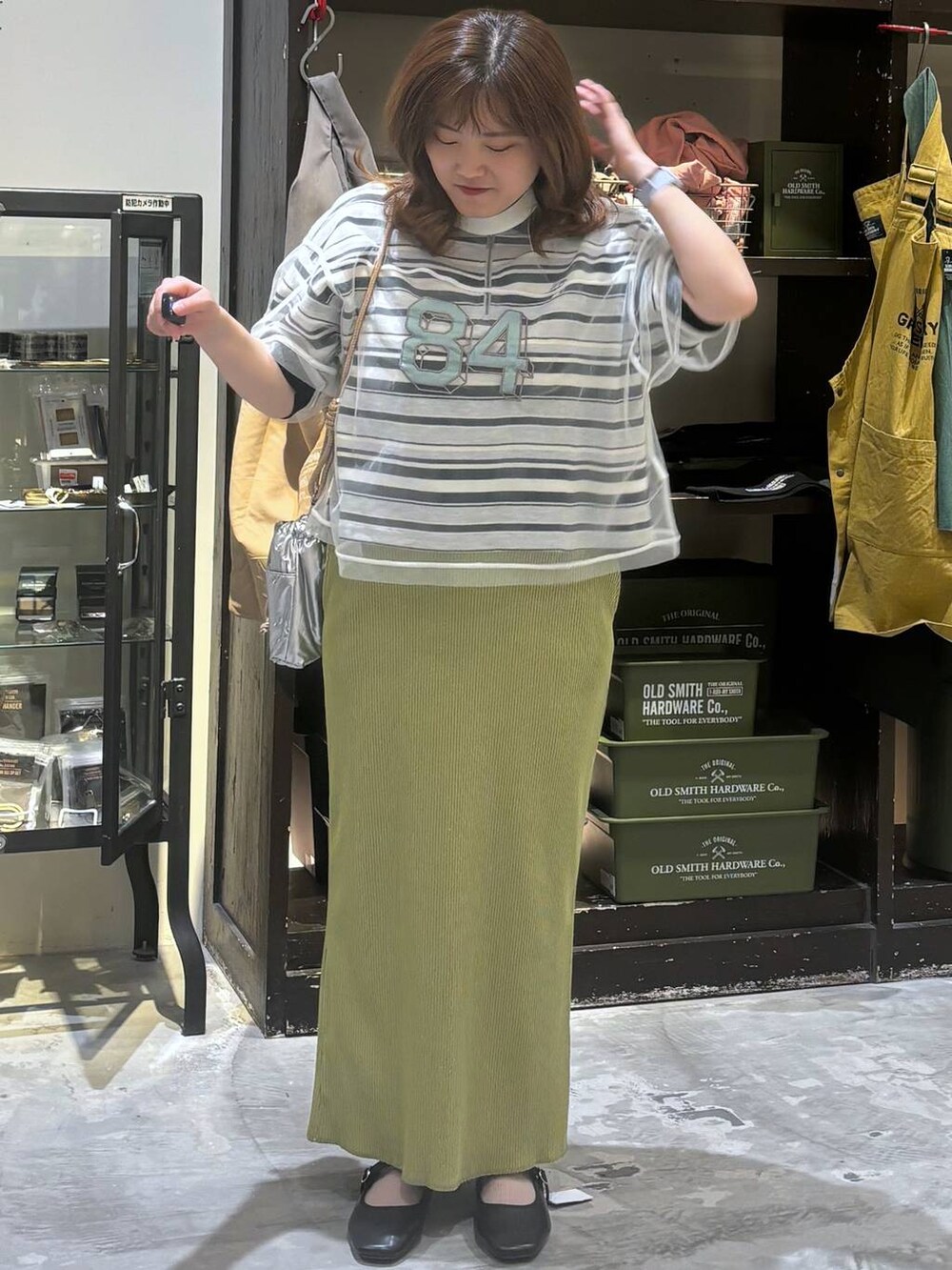 シルバー系のショルダーバッグ、その他のパンプス、グリーン系のスカートを着用したレディースの夏コーディネートの4枚目の写真
