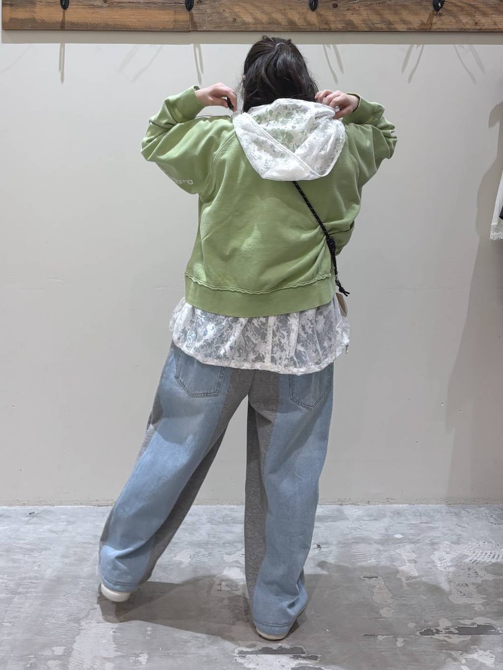 グレー系のデニムパンツ、グリーン系のショルダーバッグ、ホワイト系のベストを着用したレディースの春コーディネートの4枚目の写真