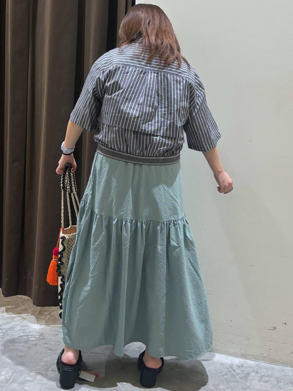 ブラック系のサンダル、グリーン系のスカート、ベージュ系のトートバッグを着用したレディースの夏コーディネートの6枚目の写真