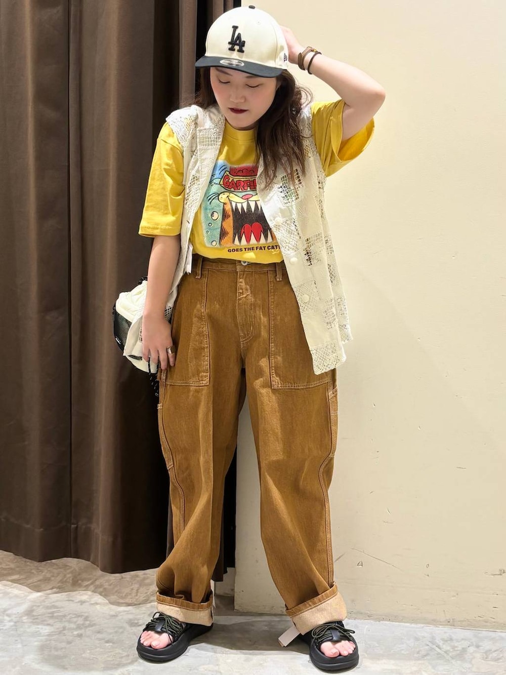 ベージュ系のベスト、ブラウン系のデニムパンツ、ブラック系のサンダルを着用したレディースの夏コーディネートの4枚目の写真