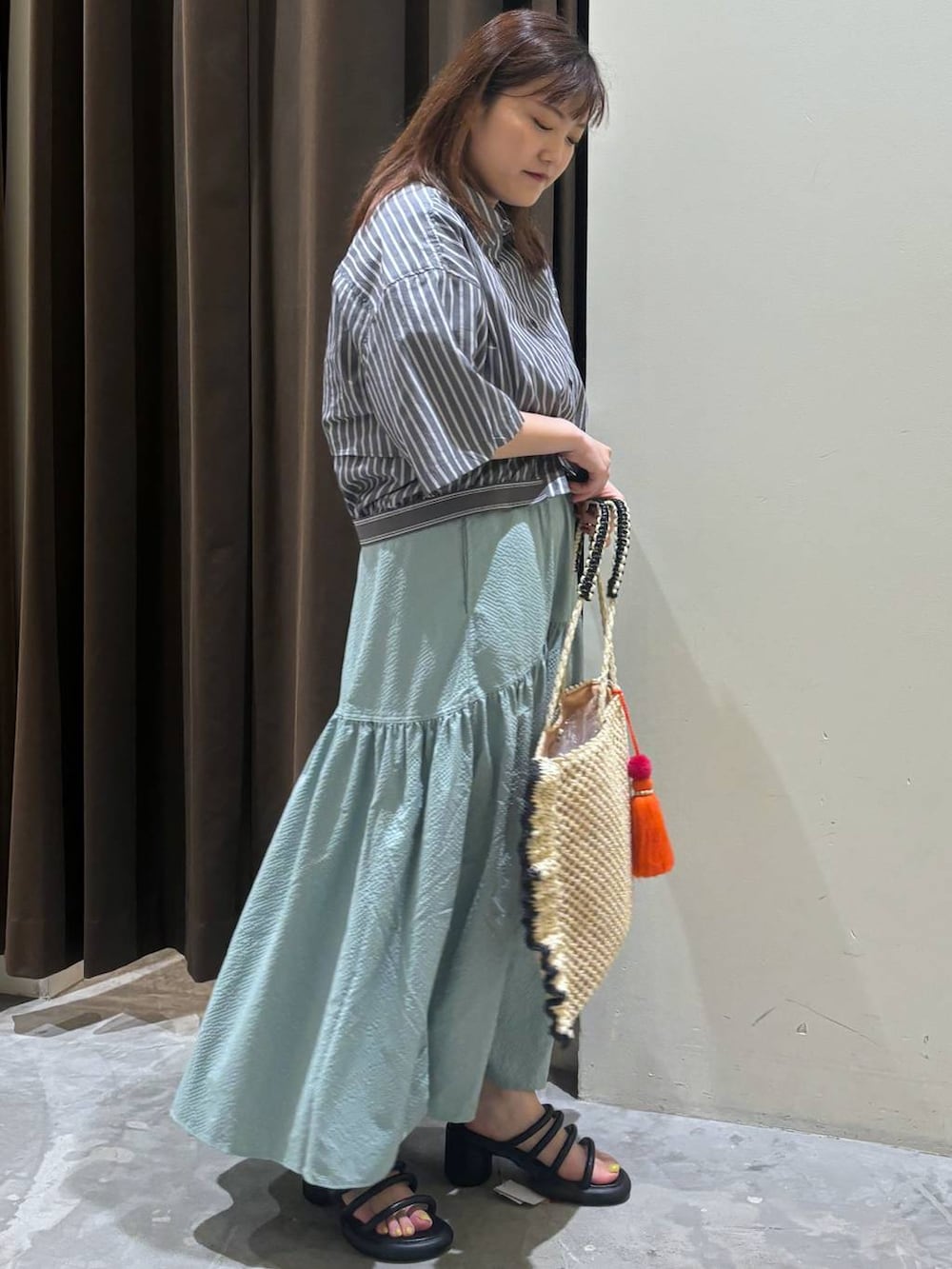 ブラック系のサンダル、グリーン系のスカート、ベージュ系のトートバッグを着用したレディースの夏コーディネートの5枚目の写真