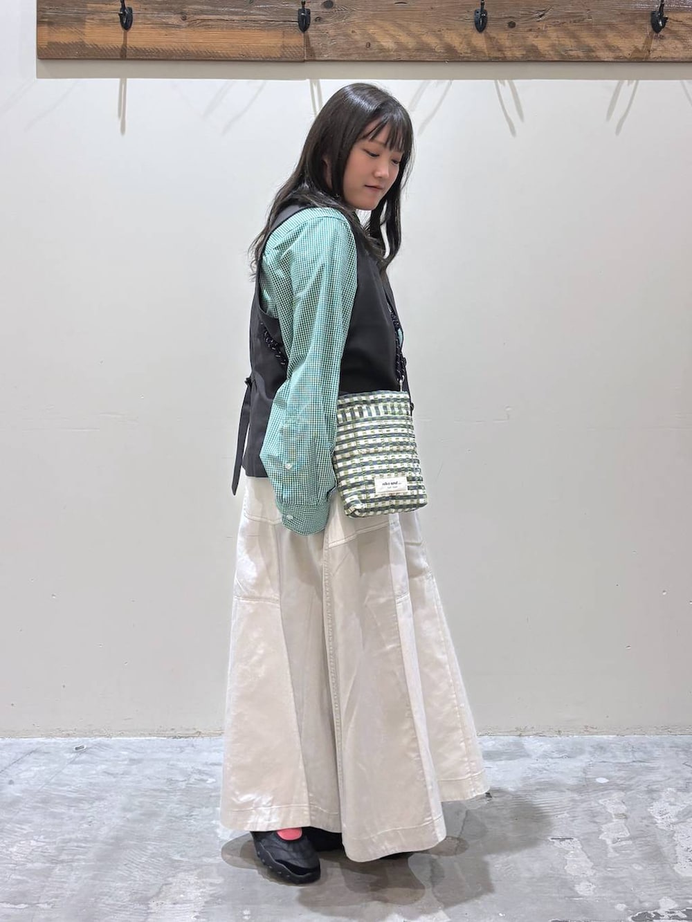 グリーン系のショルダーバッグ、ブラック系のベスト、ブラック系のバレエシューズを着用したレディースの春コーディネートの4枚目の写真