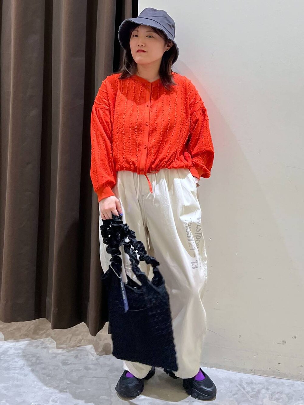 ブラック系のトートバッグ、ブラック系のスニーカー、レッド系のカーディガン/ボレロを着用したレディースの春コーディネートの3枚目の写真