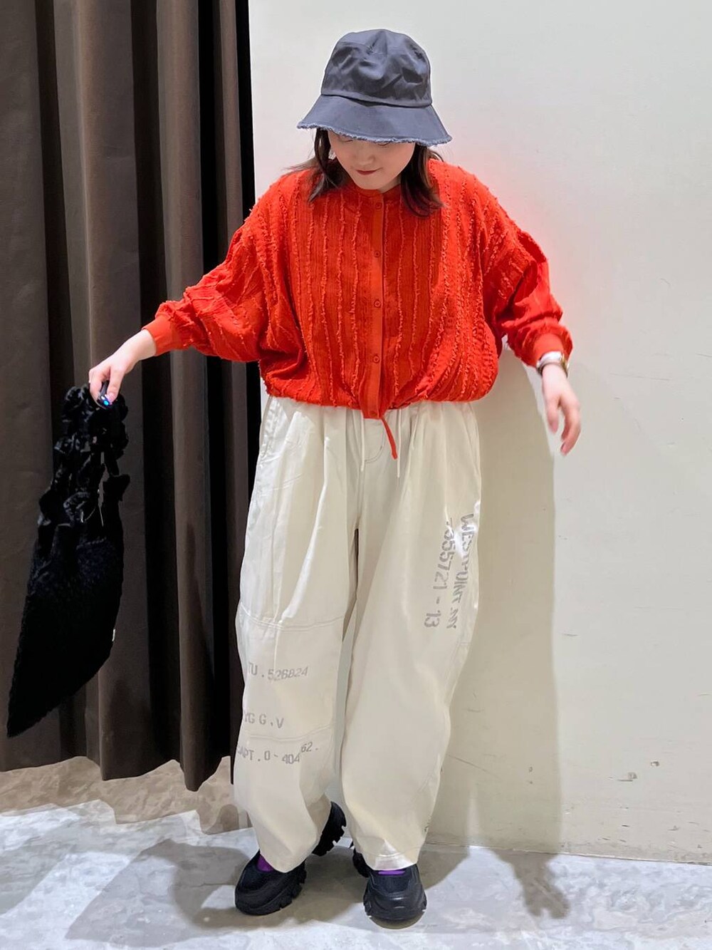 ブラック系のトートバッグ、ブラック系のスニーカー、レッド系のカーディガン/ボレロを着用したレディースの春コーディネートの2枚目の写真