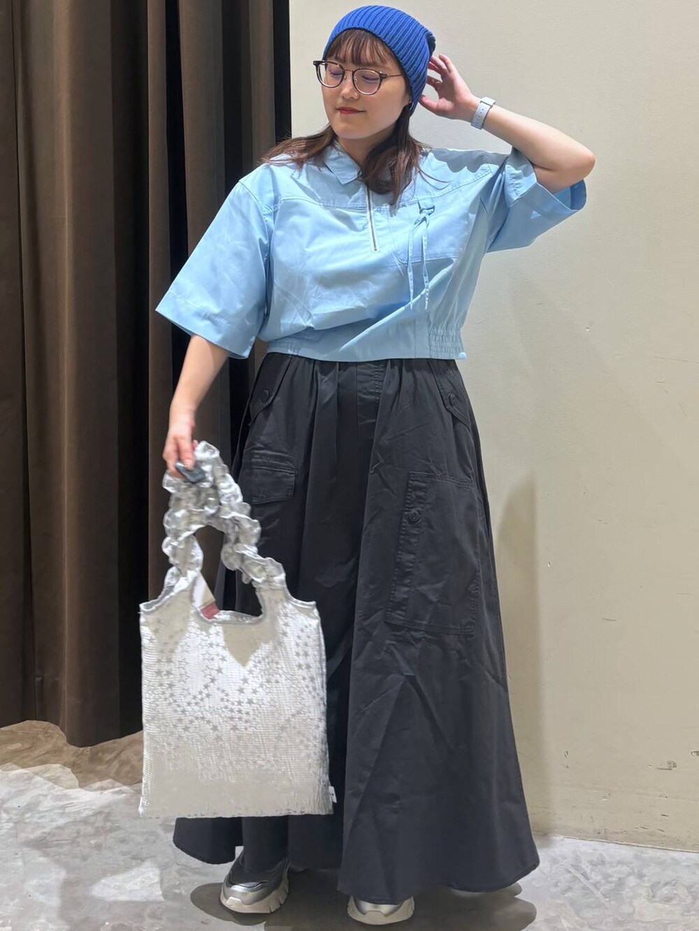 シルバー系のトートバッグ、シルバー系のスニーカー、グレー系のスカートを着用したレディースの夏コーディネートの4枚目の写真