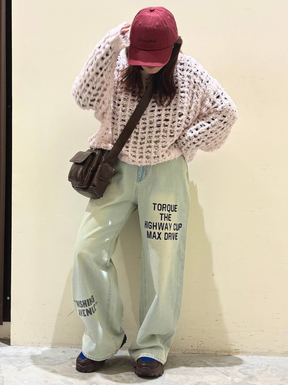 ブラウン系のスニーカー、ブラウン系のショルダーバッグ、ブルー系のデニムパンツを着用したレディースの冬コーディネートの2枚目の写真