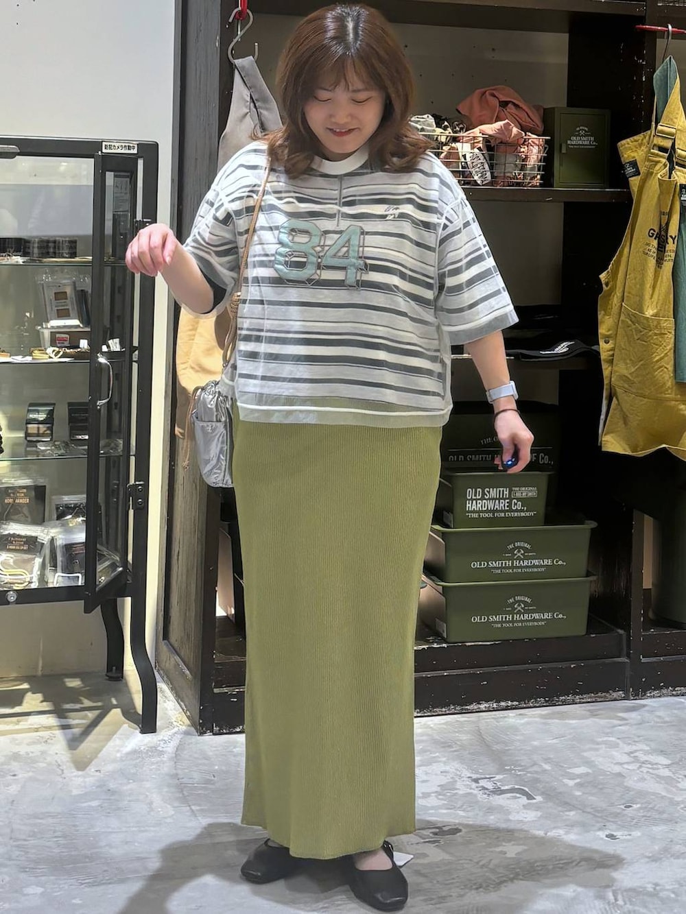 シルバー系のショルダーバッグ、その他のパンプス、グリーン系のスカートを着用したレディースの夏コーディネートの3枚目の写真