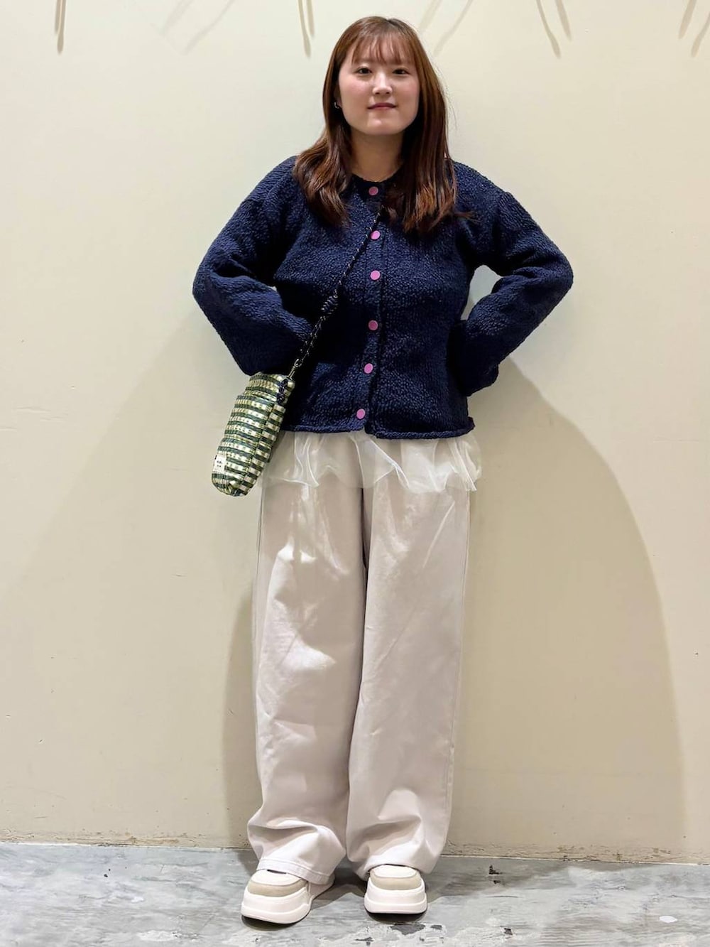 グリーン系のショルダーバッグ、ブルー系のニット/セーター、ベージュ系のチノパンツを着用したレディースの冬コーディネートの3枚目の写真