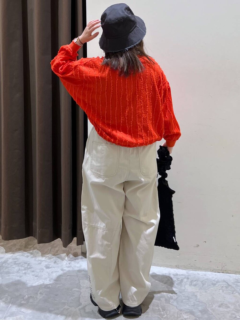 ブラック系のトートバッグ、ブラック系のスニーカー、レッド系のカーディガン/ボレロを着用したレディースの春コーディネートの4枚目の写真