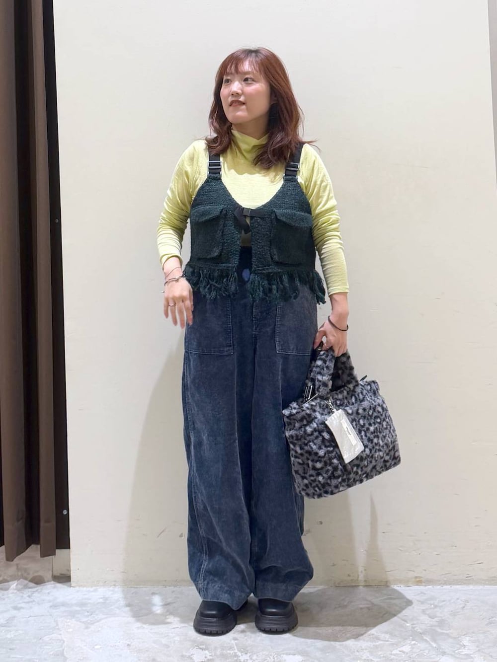 グリーン系のベスト、その他のトートバッグ、イエロー系のTシャツ/カットソーを着用したレディースの秋コーディネートの2枚目の写真
