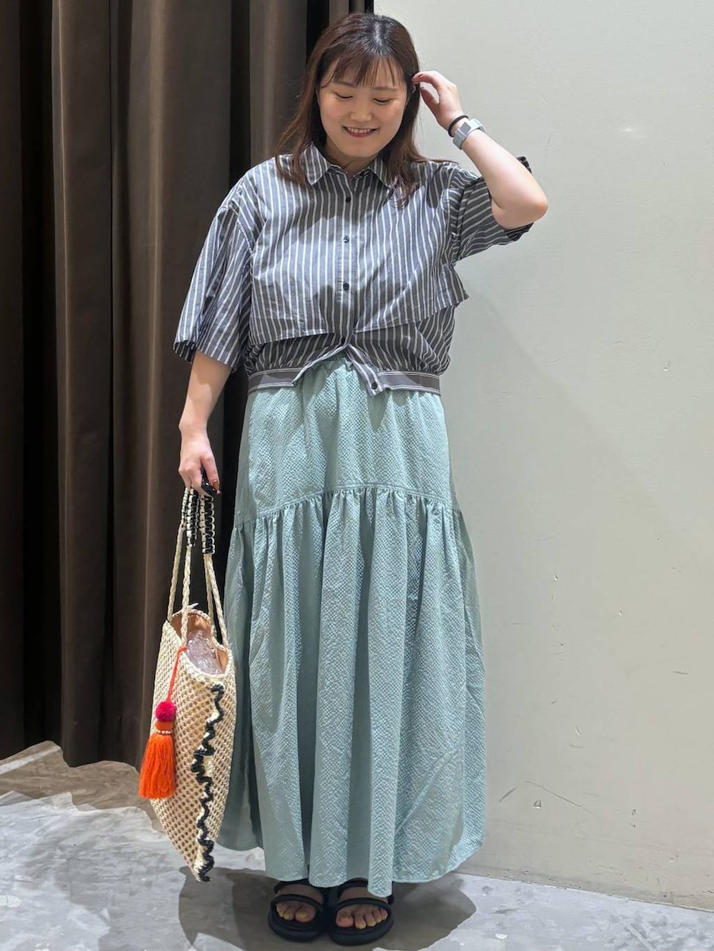 ブラック系のサンダル、グリーン系のスカート、ベージュ系のトートバッグを着用したレディースの夏コーディネートの4枚目の写真