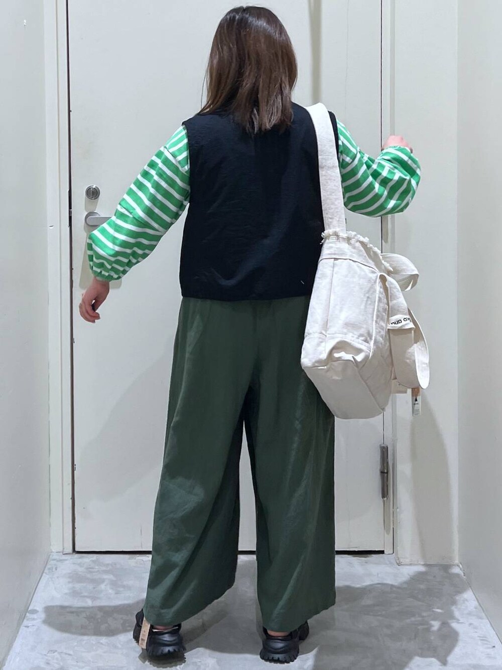 ベージュ系のショルダーバッグ、ブラック系のサンダル、ブラック系のベストを着用したレディースの春コーディネートの6枚目の写真