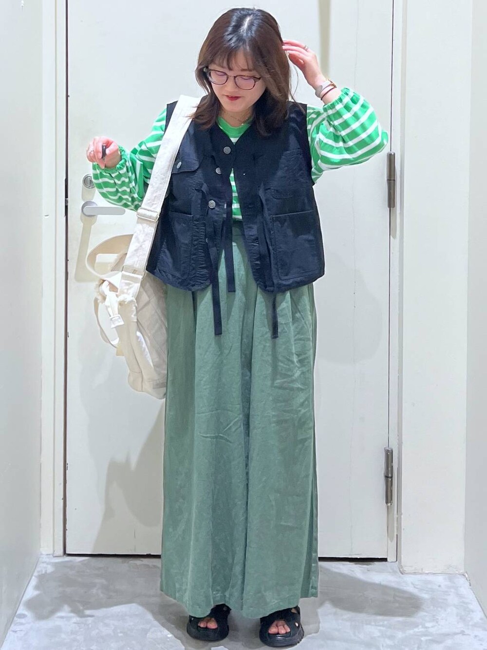 ベージュ系のショルダーバッグ、ブラック系のサンダル、ブラック系のベストを着用したレディースの春コーディネートの3枚目の写真