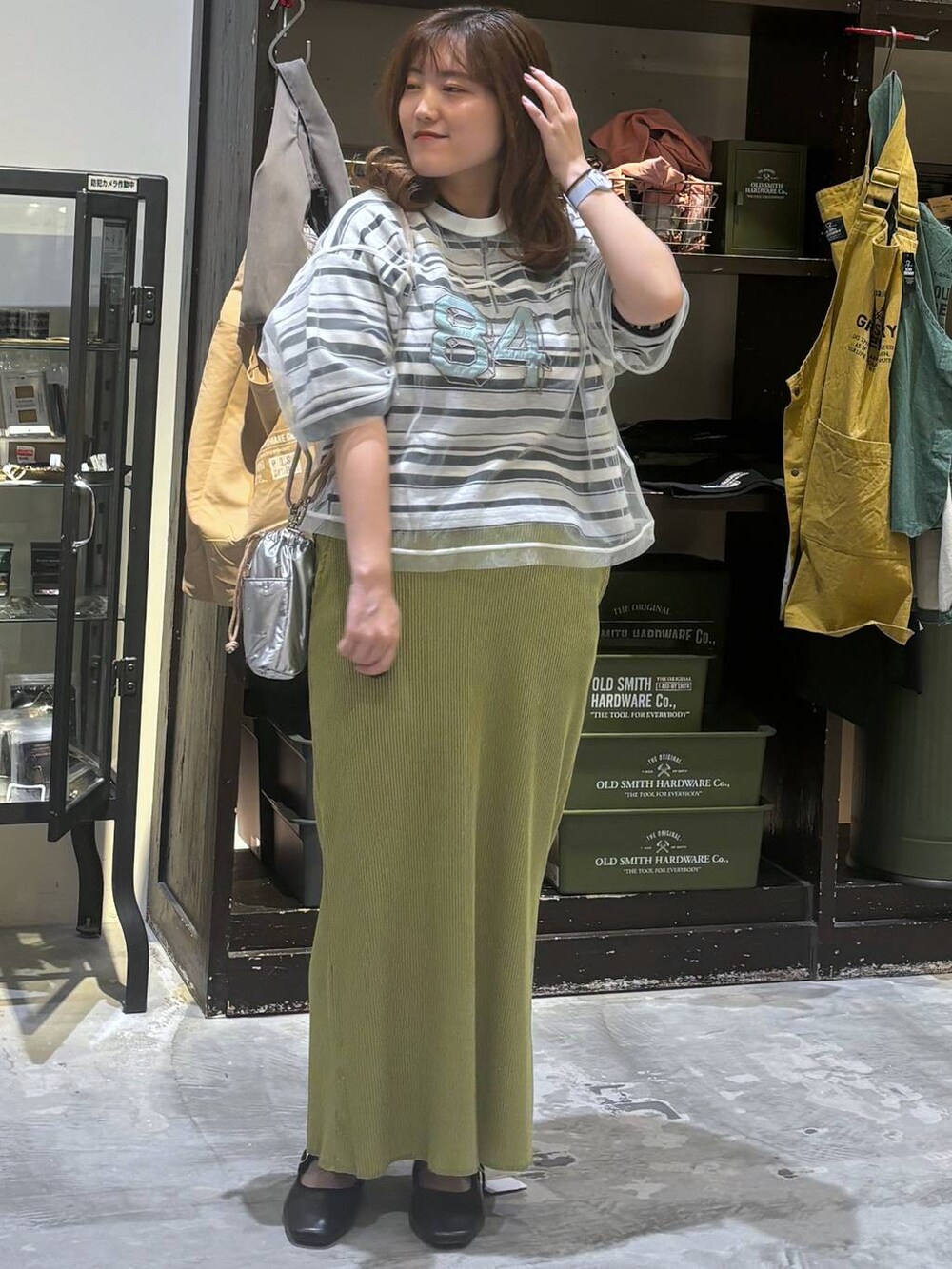 シルバー系のショルダーバッグ、その他のパンプス、グリーン系のスカートを着用したレディースの夏コーディネートの2枚目の写真