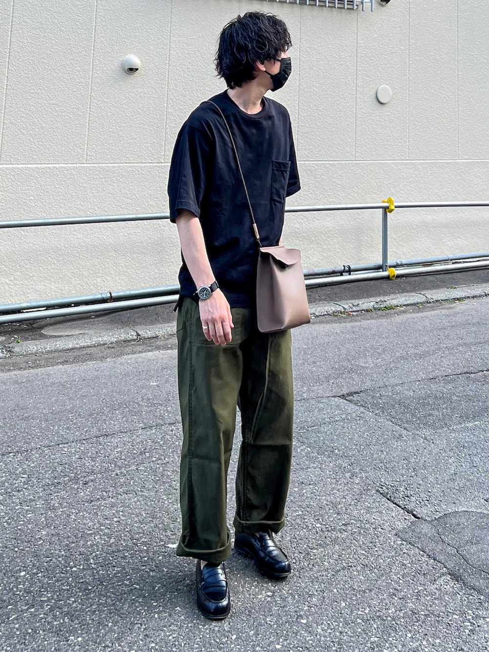 ブラック系のTシャツ/カットソー、ブラウン系のショルダーバッグ、グリーン系のパンツを着用したメンズの夏コーディネートの2枚目の写真