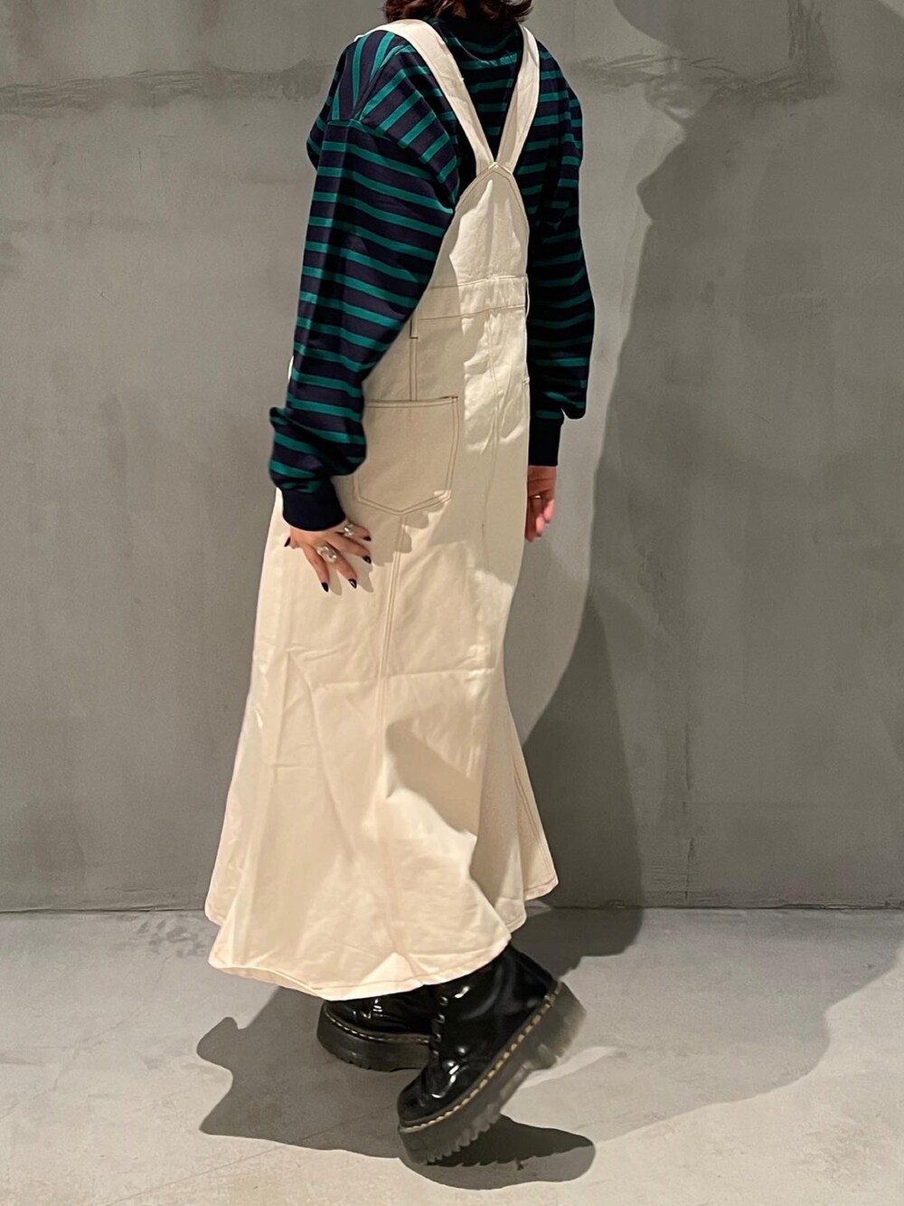 ブルー系のTシャツ/カットソー、ホワイト系のジャンパースカート、ブラック系のブーツを着用したレディースの春コーディネートの3枚目の写真