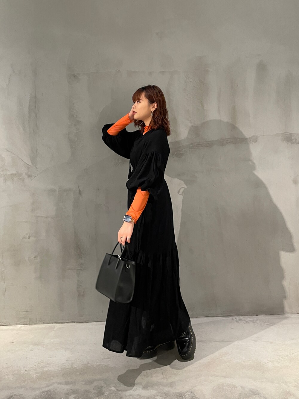 オレンジ系のTシャツ/カットソー、ブラック系のワンピース、ブラック系のトートバッグを着用したレディースの春コーディネートの2枚目の写真