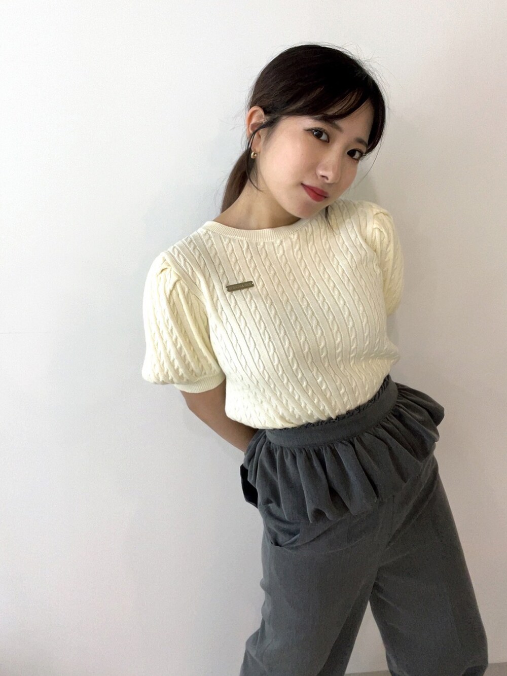 ホワイト系のニット/セーター、グレー系のスラックス、グレー系のスカートを着用したレディースの夏コーディネートの2枚目の写真