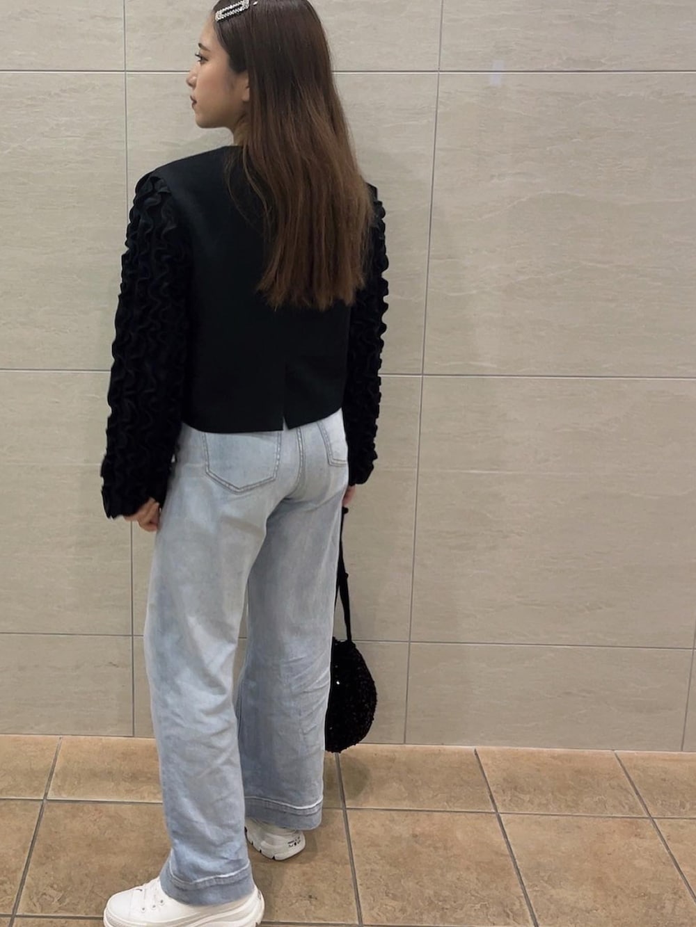 ブラック系のその他アウター、ブラック系のハンドバッグ、ブルー系のデニムパンツを着用したレディースの秋コーディネートの2枚目の写真