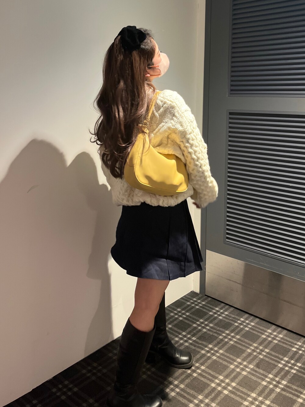 ホワイト系のニット/セーター、イエロー系のハンドバッグ、ブラック系のブーツを着用したレディースの冬コーディネートの2枚目の写真