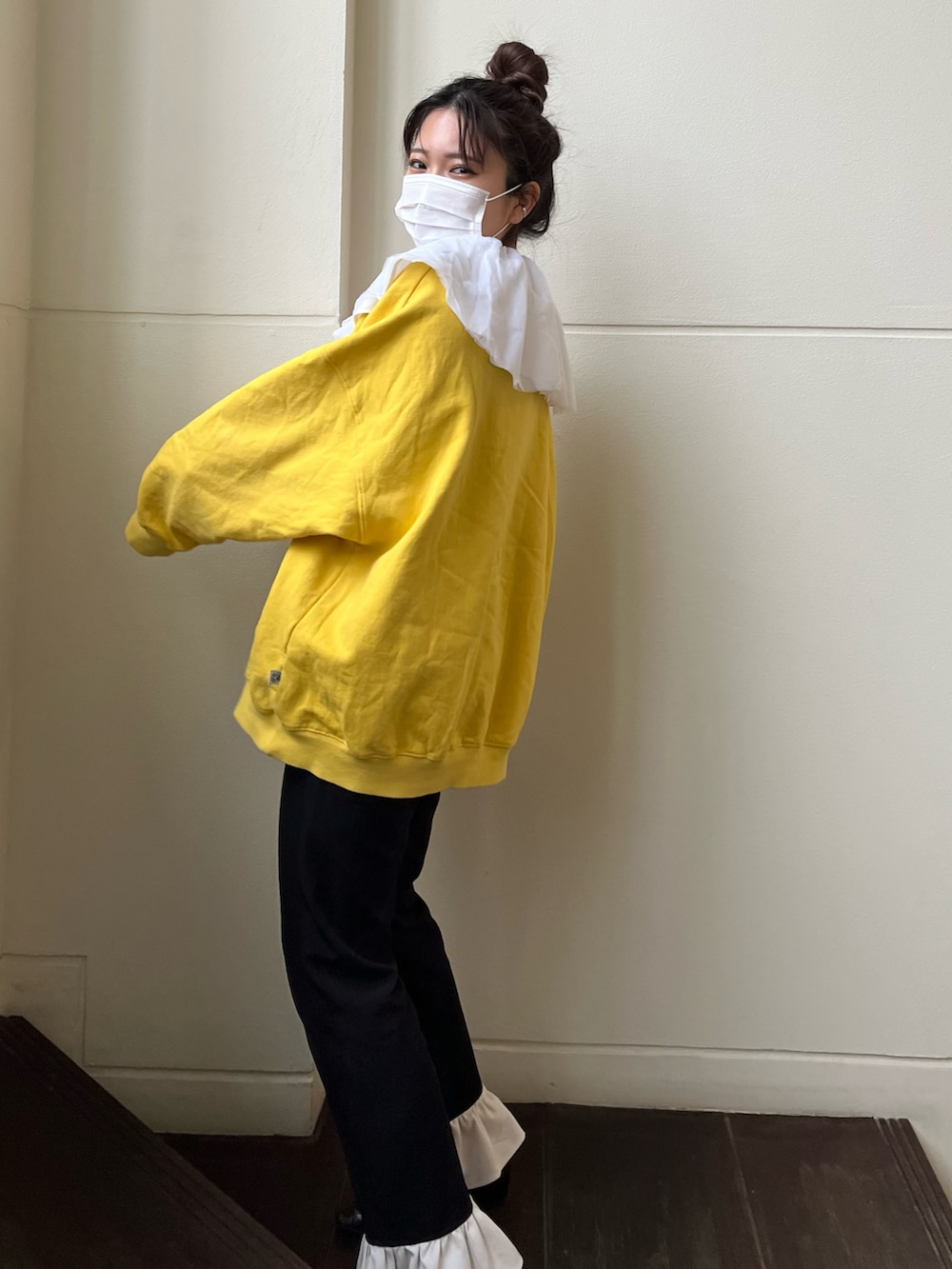 ブラック系のスラックス、イエロー系のスウェット、ブラック系のワンピースを着用したレディースの春コーディネートの2枚目の写真