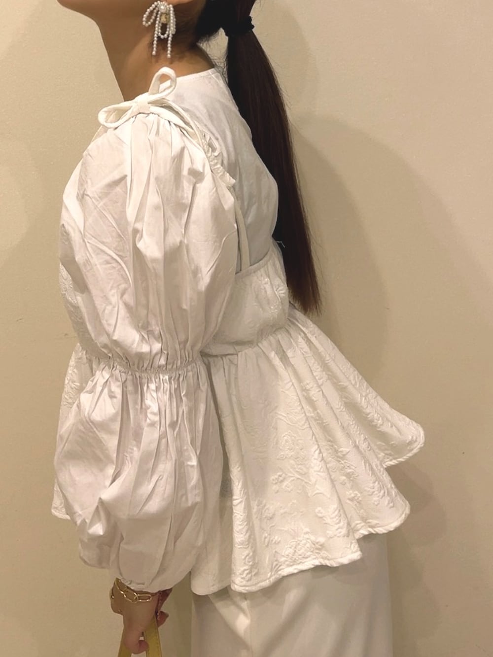 イエロー系のハンドバッグ、ホワイト系のキャミソール、ホワイト系のスカートを着用したレディースの春コーディネートの3枚目の写真