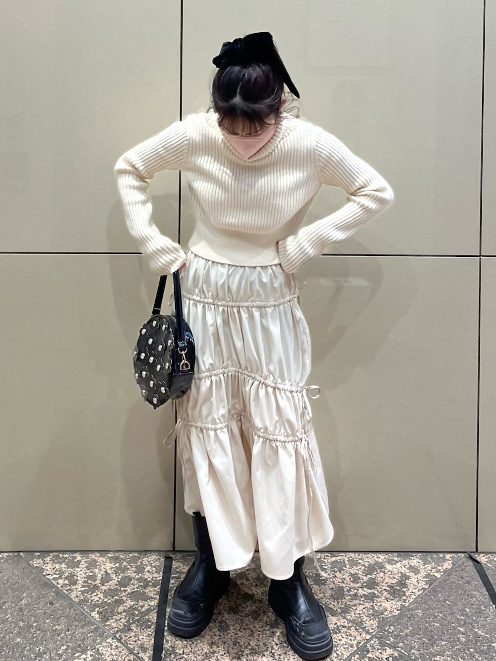 ベージュ系のニット/セーター、ベージュ系のスカート、ブラック系のショルダーバッグを着用したレディースの冬コーディネートの2枚目の写真