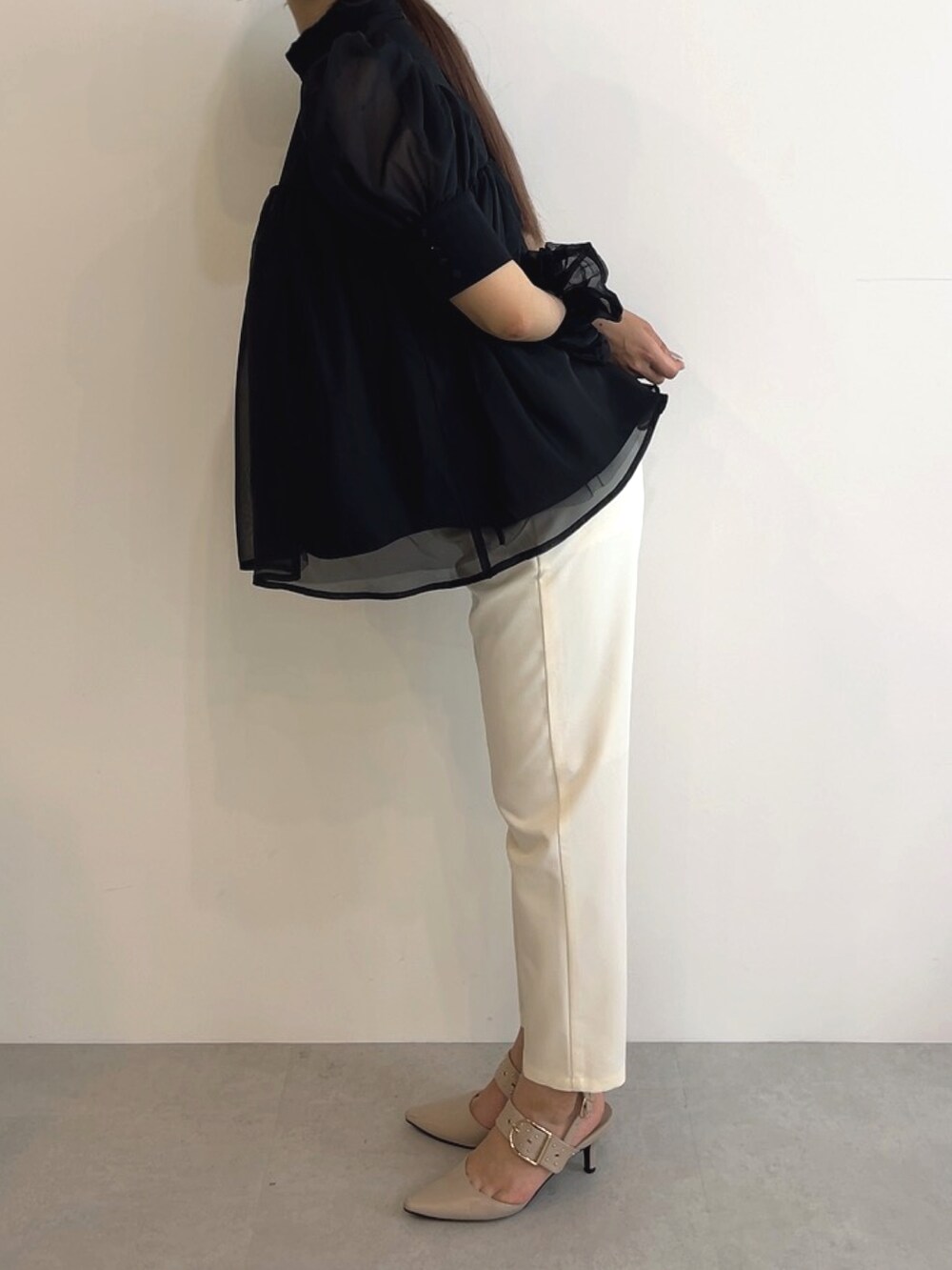 ブラック系のトップス、ホワイト系のスラックスを着用したレディースの夏コーディネートの2枚目の写真