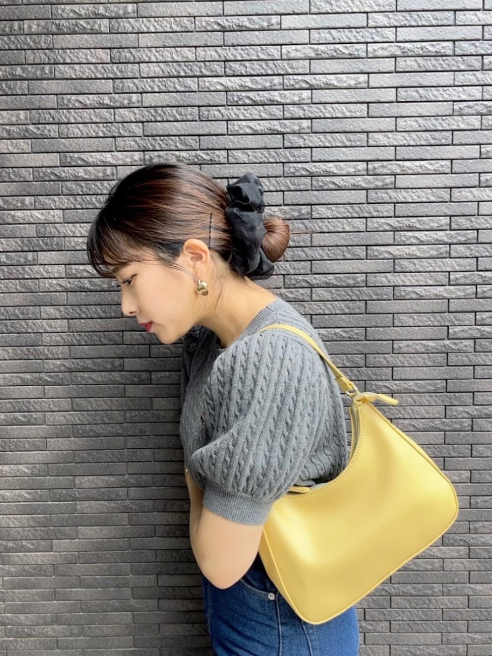 イエロー系のハンドバッグ、グレー系のニット/セーターを着用したレディースの春コーディネートの2枚目の写真