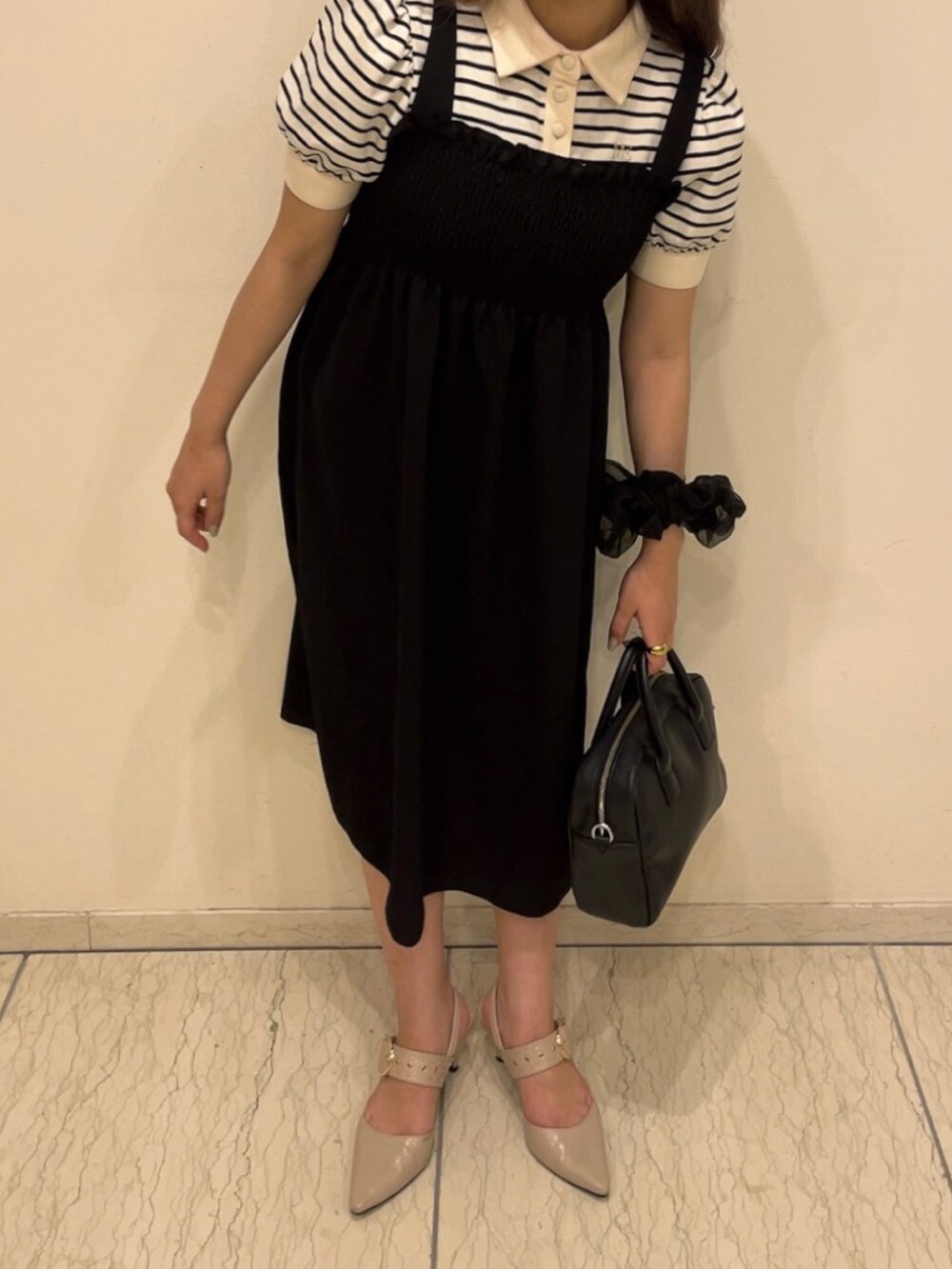 ホワイト系のポロシャツ、ブラック系のワンピース/ドレス、ブラック系のバッグを着用したレディースの夏コーディネートの2枚目の写真