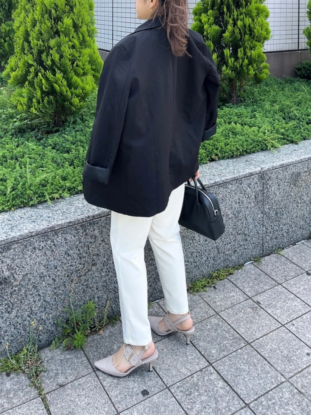 ブラック系のショルダーバッグ、ホワイト系のポロシャツ、ベージュ系のパンプスを着用したレディースの夏コーディネートの2枚目の写真