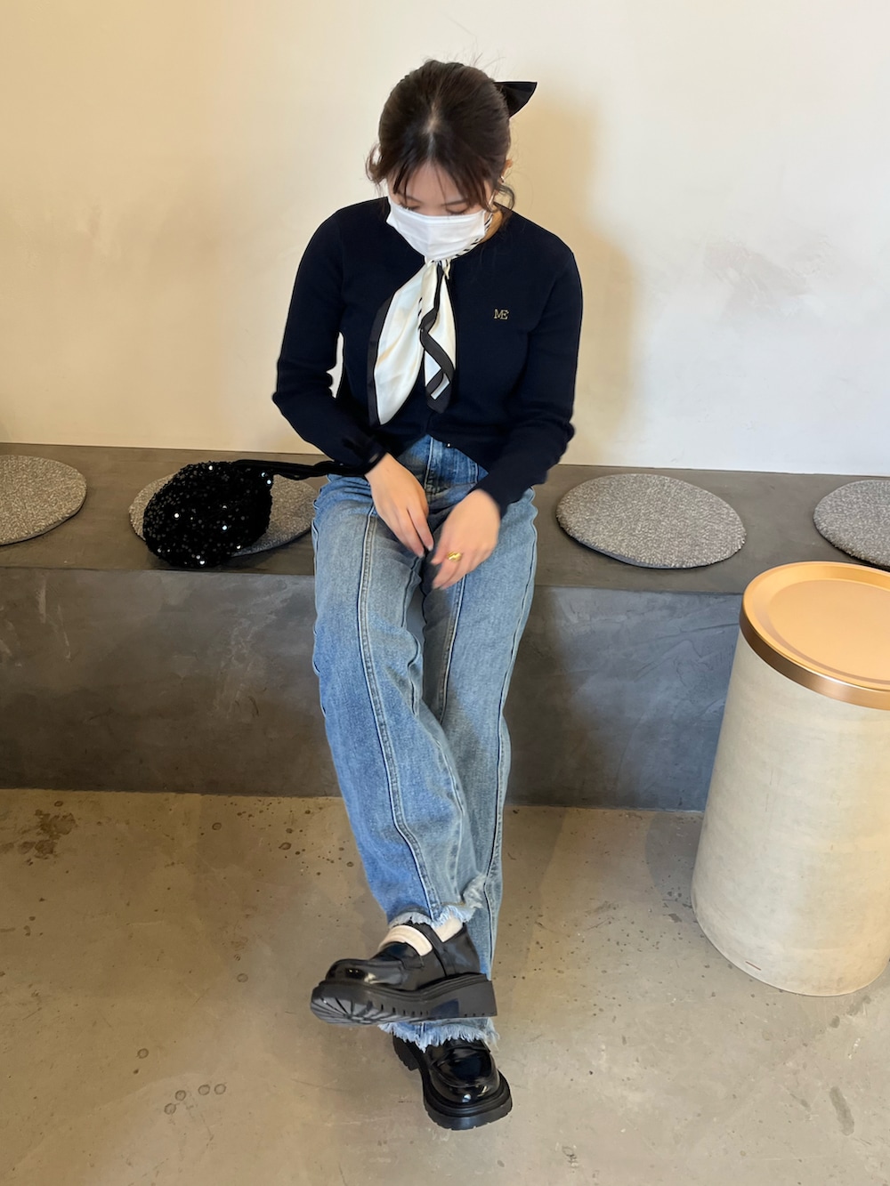 ブラック系のハンドバッグ、ブルー系のカーディガン/ボレロ、ホワイト系のバンダナ/スカーフを着用したレディースの春コーディネートの2枚目の写真