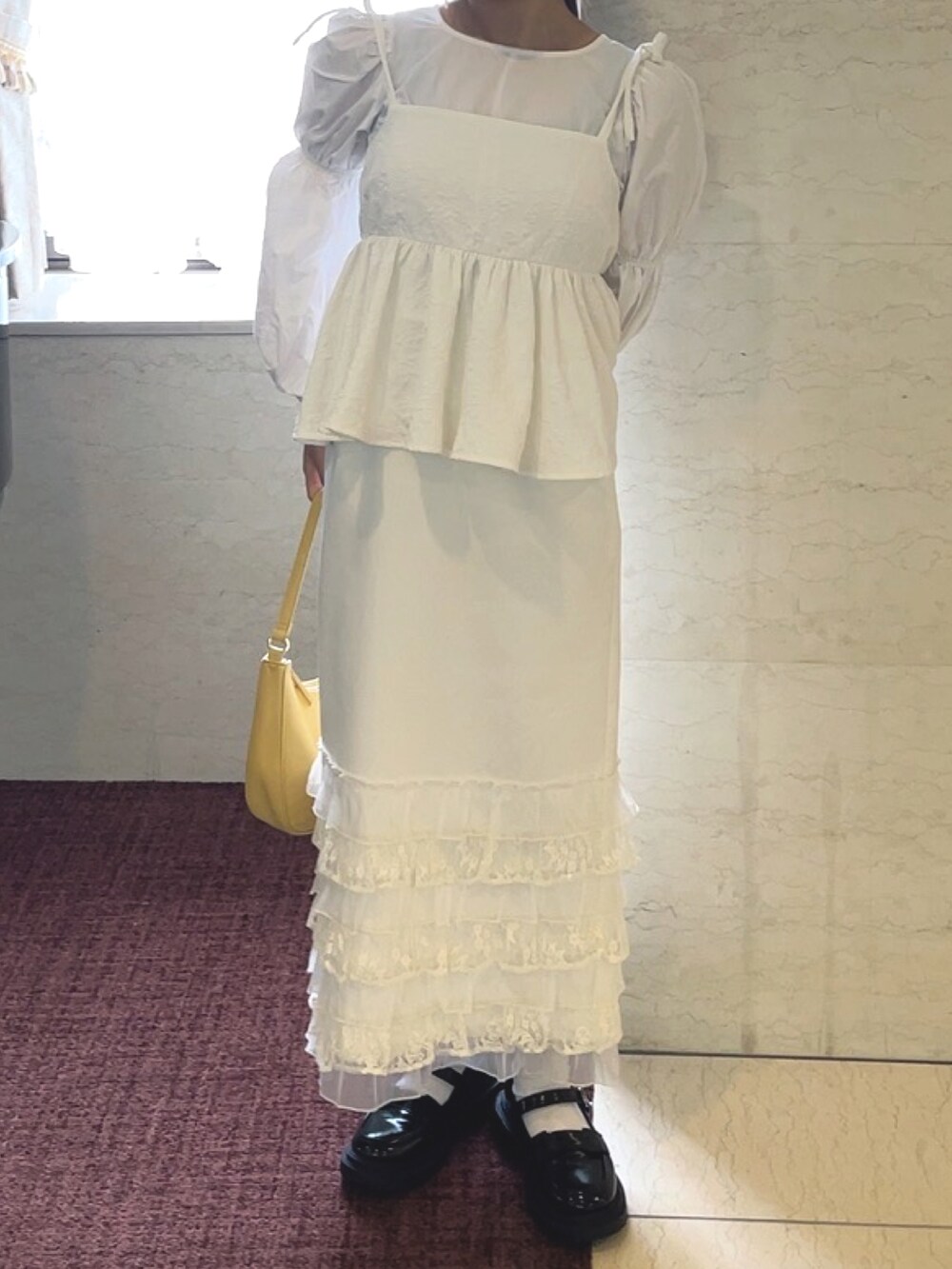 イエロー系のハンドバッグ、ホワイト系のキャミソール、ホワイト系のスカートを着用したレディースの春コーディネートの2枚目の写真