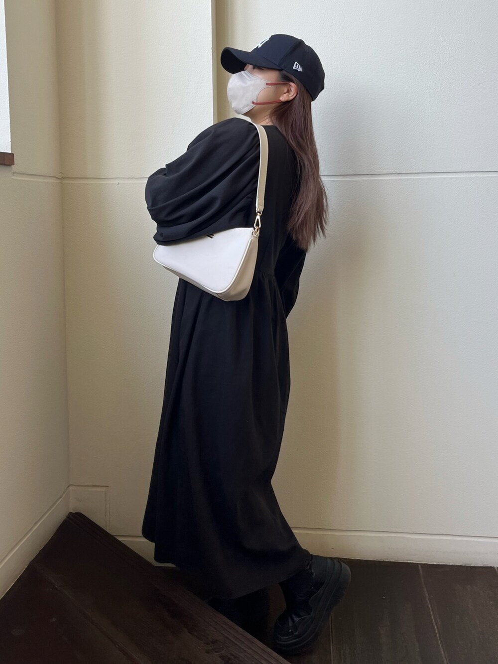 ホワイト系のショルダーバッグ、ブラック系のワンピース、ブルー系のキャップを着用したレディースの冬コーディネートの2枚目の写真