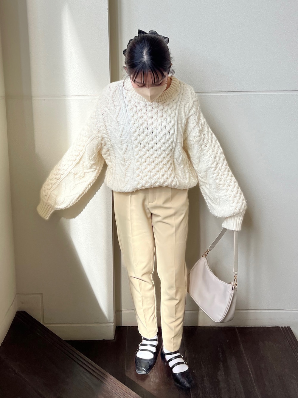 ホワイト系のニット/セーター、イエロー系のスラックス、ホワイト系のショルダーバッグを着用したレディースの春コーディネートの2枚目の写真