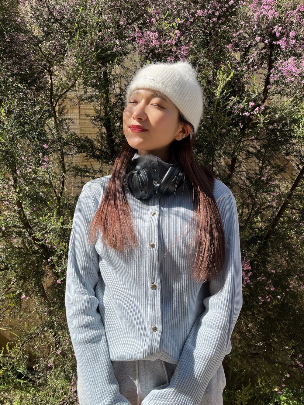 グレー系のスウェットパンツ、ブルー系のカーディガン/ボレロ、ホワイト系のニットキャップ/ビーニーを着用したレディースの春コーディネートの2枚目の写真