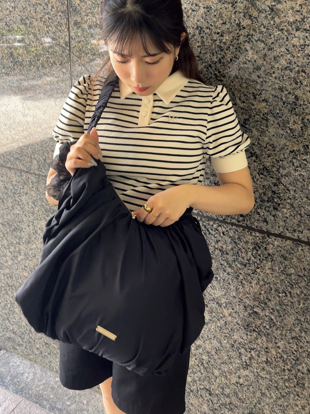 ホワイト系のポロシャツ、ブラック系のショルダーバッグ、ブラック系のパンツを着用したレディースの夏コーディネートの2枚目の写真